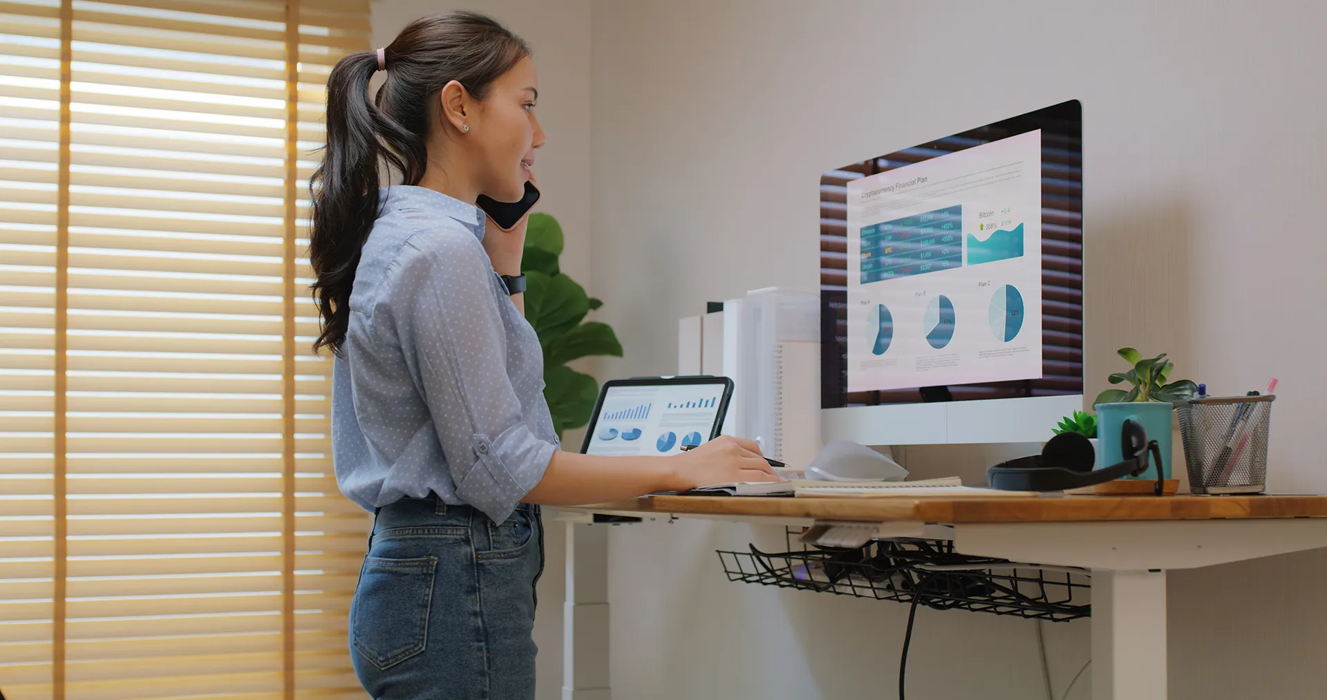 Electric adjustable standing desk in small office workspace