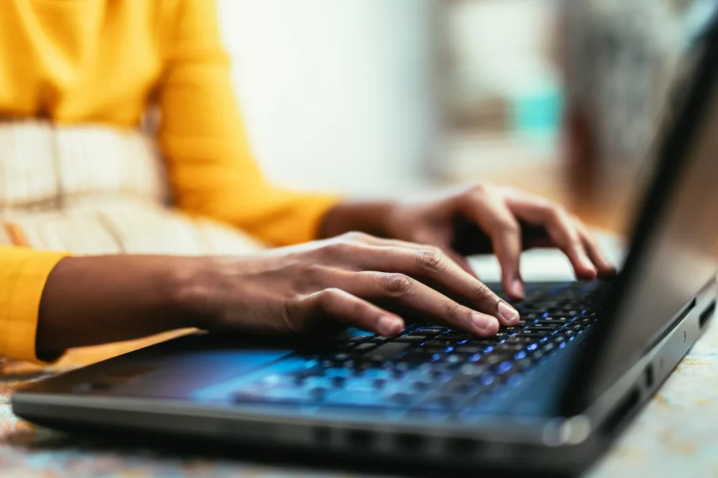 Hands typing on a laptop keyboard