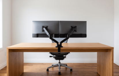 Clean Scandinavian home office desk with two matching monitors on a monitor arm in soft natural light